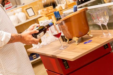 Plano fechado no sommelier da Grand Cru, com foco em suas mãos servindo vinho tinto na taça de uma cliente. (Lançamento Casa Riachuelo, Rua Oscar Freire, São Paulo, Fotos Bruno Arita)'