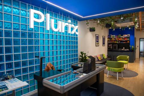Entrada da sede da Plurix em São Paulo, com o logo da empresa e uma mesa decorada em formato de caixa de supermercado, marcando o Dia das Crianças 2025. (Evento Plurix, São Paulo, Fotógrafo Bruno Arita)'