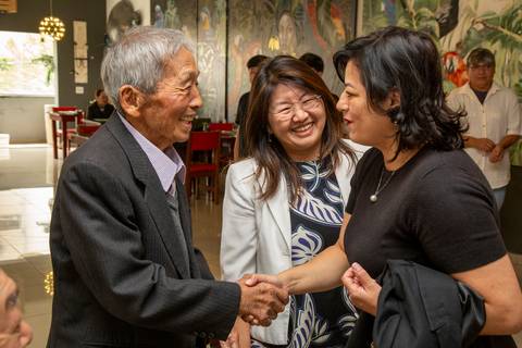 O pai dos aniversariantes cumprimentando uma convidada em momento alegre, enquanto Miki sorri ao fundo. (Aniversário em Dobro, Nanako, São Paulo, Fotógrafo Bruno Arita)'