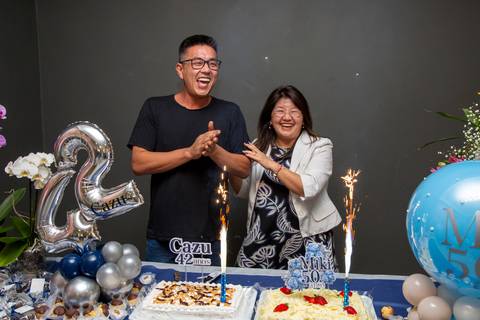 Os aniversariantes (Miki e Cazu) cantando 'Parabéns' juntos, em um momento de celebração compartilhada. (Aniversário em Dobro, Nanako, São Paulo, Fotógrafo Bruno Arita)'