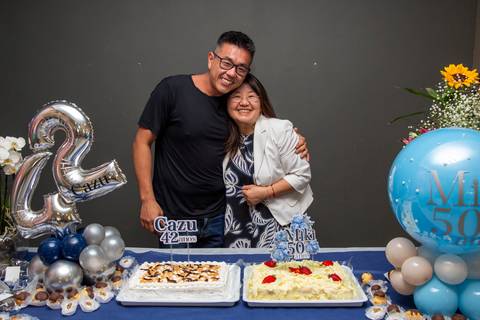Os aniversariantes (Miki e Cazu) posando para foto na mesa do bolo, com o bolo de aniversário em destaque. (Aniversário em Dobro, Nanako, São Paulo, Fotógrafo Bruno Arita)'