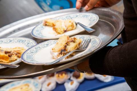 Plano fechado do bolo de aniversário sendo servido em pratos de porcelana, em uma bandeja, destacando a sobremesa. (Aniversário em Dobro, Nanako, São Paulo, Fotógrafo Bruno Arita)'