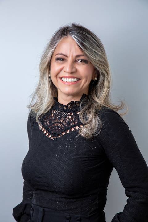 Retrato de Mulher com fundo branco, sorrindo de forma simpática, em traje preto elegante com detalhes rendados. (Retrato Corporativo, São Paulo, Fotógrafo Bruno Arita)'