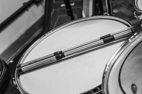 Plano detalhe (preto e branco) das baquetas de varetas repousando sobre a caixa da bateria. (Banda Madressilva, Ensaio Musical, Fotos Bruno Arita)'