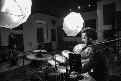 Foto de making of (preto e branco) do baterista Bruno Pigat, com foco e regra dos terços na direita e modificadores de luz visíveis no estúdio. (Banda Madressilva, Ensaio Musical, Fotos Bruno Arita)'