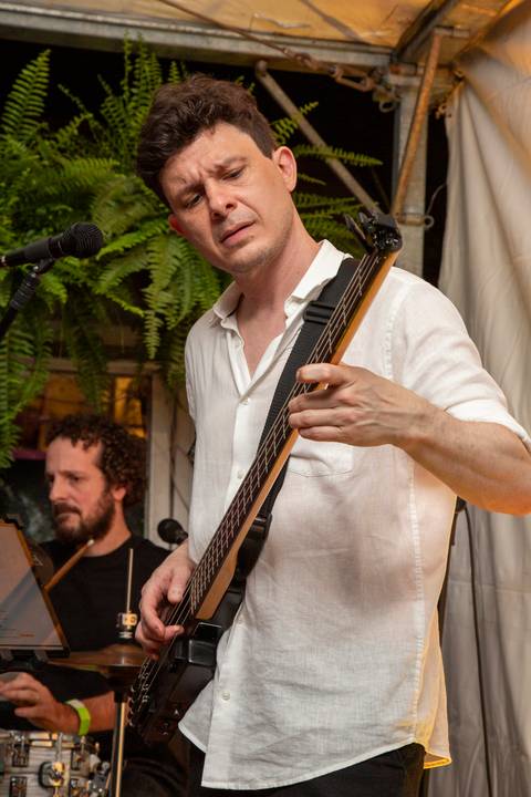 Baixista Marco Augusto tocando compenetrado, com o baterista Bruno Pigat da Madressilva ao fundo. (Ninfa Flores, São Paulo, Fotos Bruno Arita)'