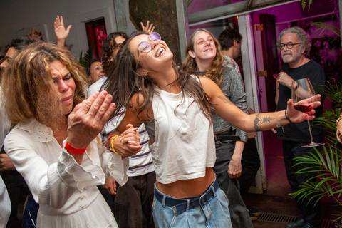 Convidada na plateia pulando e dançando, com braços abertos e cabeça erguida, expressando a alegria do evento. (Ninfa Flores, São Paulo, Fotos Bruno Arita)'