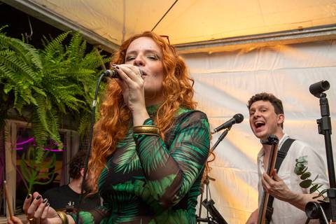 Vocalista Agnes Gomes em primeiro plano e o baixista Marco Augusto da Madressilva no segundo plano, cantando juntos. (Ninfa Flores, São Paulo, Fotos Bruno Arita)'