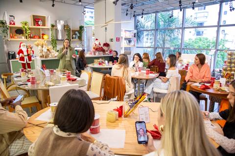 Plano aberto mostrando os participantes do Workshop de Natal nas mesas, com a especialista Simone Galvão ao fundo. (Westwing Moema, São Paulo, Fotos Bruno Arita)'