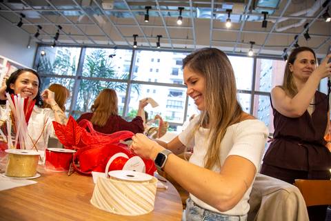 Influencer Paula Putz montando seu laço vermelho, sorrindo e se divertindo na oficina do Workshop de Natal da Westwing Moema. (Westwing Moema, São Paulo, Fotos Bruno Arita)'