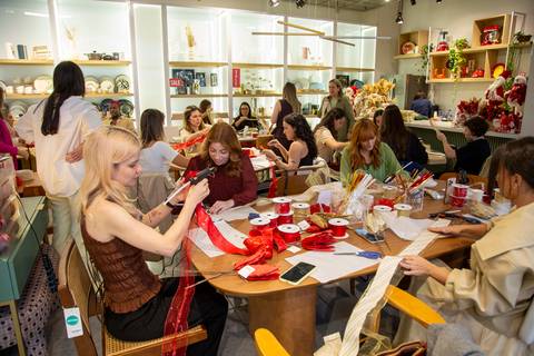 Plano aberto das influencers Stella Conti, Maitê Volpini e Luiza Panucci na mesa, focadas na criação dos laços. (Westwing Moema, São Paulo, Fotos Bruno Arita)'