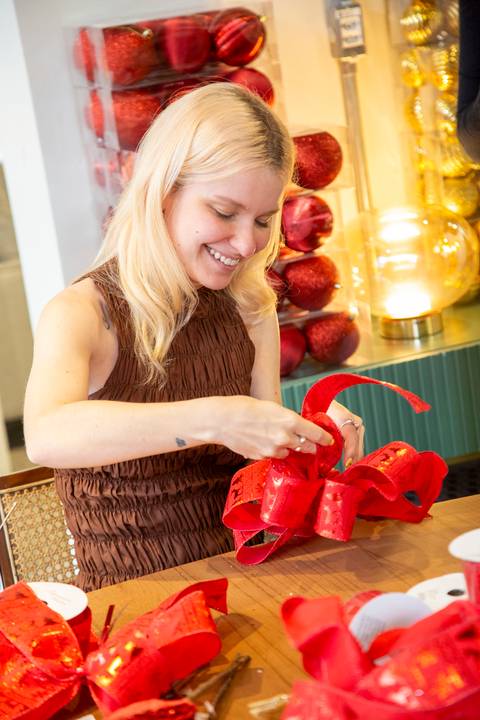 Influencer Stella Conti (@stellaconti) sorrindo em momento descontraído, concentrada na finalização do seu laço. (Westwing Moema, São Paulo, Fotos Bruno Arita)'
