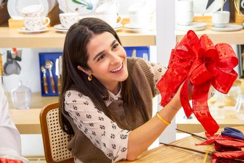 Influencer Bela Vasconcelos (@belavasconcelos.arq) sorrindo e segurando seu laço duplo de Natal pronto. (Westwing Moema, São Paulo, Fotos Bruno Arita)'