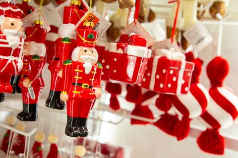 Plano detalhe de itens pequenos para pendurar na árvore de Natal, como soldadinhos e mini caixas de presentes vermelhas. (Westwing Moema, São Paulo, Fotos Bruno Arita)'