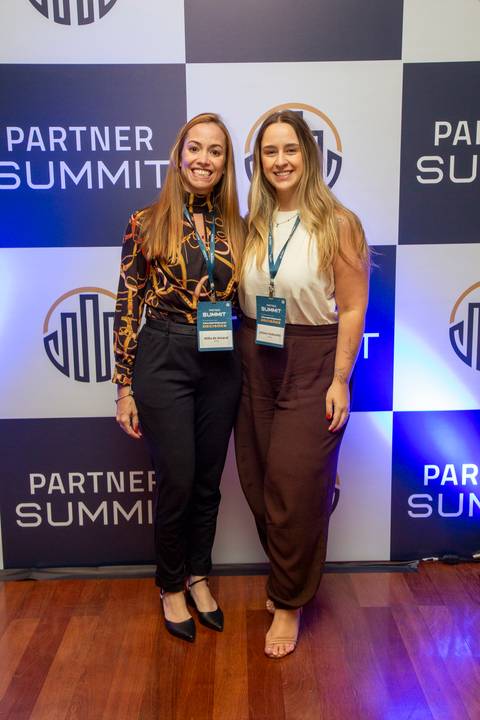Duas participantes posando para foto juntas em frente ao backdrop do Partner Summit da PSE. (Grand Hyatt SP, Evento Corporativo, Fotos Bruno Arita)'