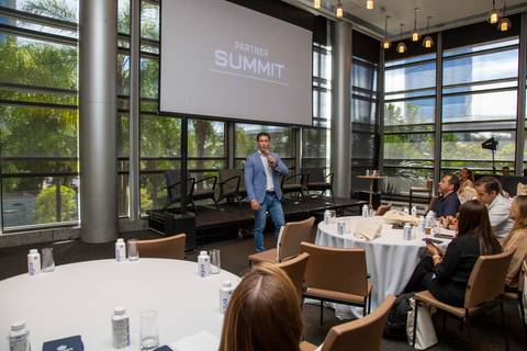 Plano aberto do salão de eventos. Anfitrião da Partner PSE abrindo o Summit ao microfone, com telão projetando a marca. (Grand Hyatt SP, Evento Corporativo, Fotos Bruno Arita)'