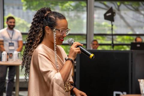 Palestrante (mulher negra) em plano médio, sorrindo e olhando para o público durante seu painel de Real Estate. (Grand Hyatt SP, Evento Corporativo, Fotos Bruno Arita)'