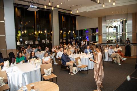 Plano aberto mostrando a palestrante no palco e o salão com todos os participantes sentados à mesa. (Grand Hyatt SP, Evento Corporativo, Fotos Bruno Arita)'