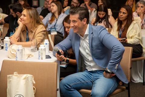 Anfitrião da Partner PSE sorrindo, sentado e acompanhando o debate em plano mais fechado. (Grand Hyatt SP, Evento Corporativo, Fotos Bruno Arita)'