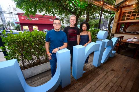 Retrato de participantes sorridentes atrás do letreiro de madeira da Plurix, registrando a celebração de fim de ano. (Confraternização Plurix, São Paulo, Fotos Bruno Arita)'