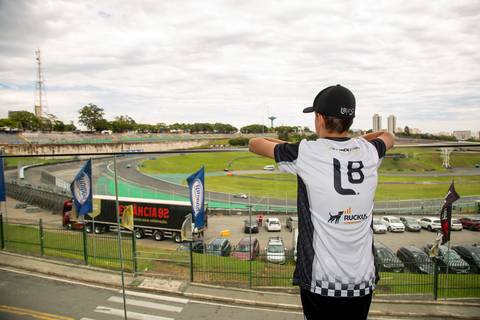 Participante em primeiro plano, usando camisa da L8 e Ruckus, observando a pista de Interlagos ao fundo. (Stock Car 2025, Interlagos, Fotos Bruno Arita)'
