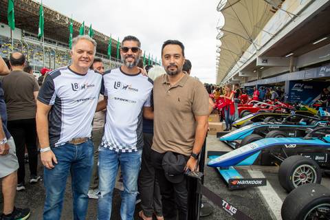 Participantes posando para foto em frente aos boxes dos carros da F4. (L8 Group, Ruckus Networks, Fotos Bruno Arita)'