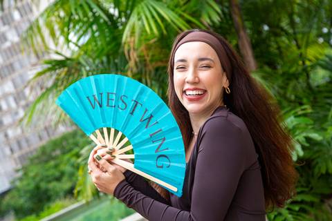 Bruna Vieira sorridente segurando o leque da Westwing em plano médio na área externa. (Lançamento Verão 2026, São Paulo, Fotos Bruno Arita)'