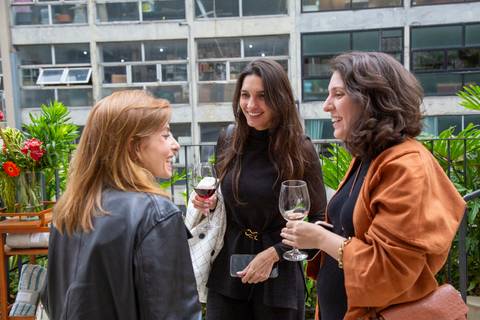 Participantes conversando e tomando drinks na área externa com vista para o centro de São Paulo. (Evento Westwing, Fotos Bruno Arita)'