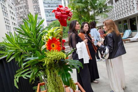 Convidados ao fundo e flores decorativas em primeiro plano na varanda do bar P.arador. (Evento Westwing, São Paulo, Fotos Bruno Arita)'