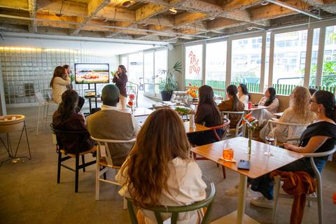 Plano aberto mostrando o público sentado e a tela de apresentação ao fundo no bar P.arador. (Lançamento Westwing, Fotos Bruno Arita)'