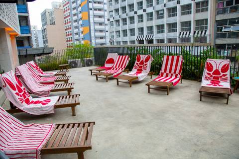 Plano aberto de espreguiçadeiras com toalhas vermelhas da nova coleção Westwing e Buddemeyer na área externa. (P.arador, São Paulo, Fotos Bruno Arita)'