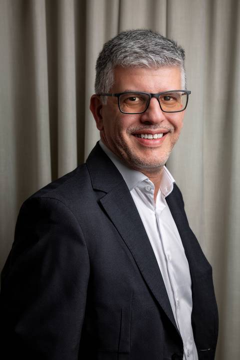 Retrato vertical colorido de Fábio Rocha sorridente, vestindo blazer escuro e camisa clara, transmitindo confiança e simpatia. (Retrato Corporativo, Fotos Bruno Arita)'