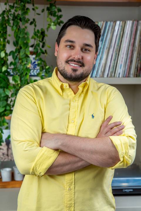 Retrato de rosto (close-up) de Tainan Salvador com sorriso amigável, vestindo camisa amarela clara em ambiente iluminado e acolhedor. (Branding Pessoal, Fotos Bruno Arita)'