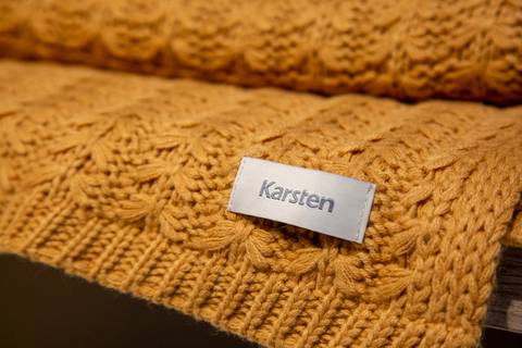 Plano fechado da etiqueta Karsten em toalha de mesa marrom, enfatizando o branding e o acabamento. (Distrito Anhembi, Fotos Bruno Arita)'