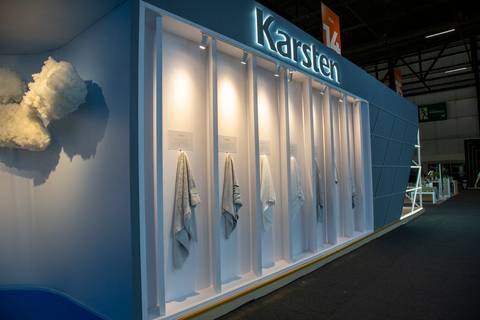 Área externa do estande com toalhas penduradas em ganchos e logotipo da Karsten iluminado ao fundo. (Distrito Anhembi, Fotos Bruno Arita)'