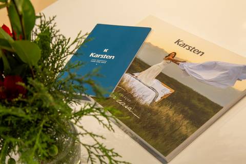 Foto criativa de catálogo e vaso de flor sobre mesa de atendimento no estande da Karsten. (ABUP Show 2026, Fotos Bruno Arita)'