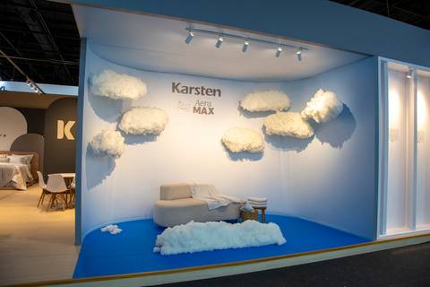 Espaço instagramável da Karsten com sofá, chão azul e parede decorada com nuvens, simulando um céu. (ABUP Show 2026, Fotos Bruno Arita)'