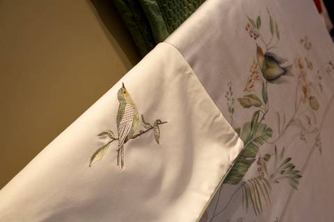 Plano detalhe de lençóis pendurados com bordados delicados de pássaros e galhos. (Design de Produto, Fotos Bruno Arita)'