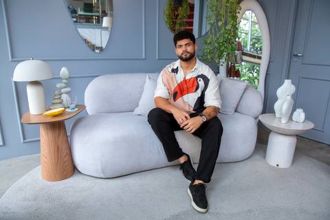O arquiteto João Gabriel em pose editorial, sentado em sofá de design na loja Westwing. Fotografia de embaixadores por Bruno Arita.'
