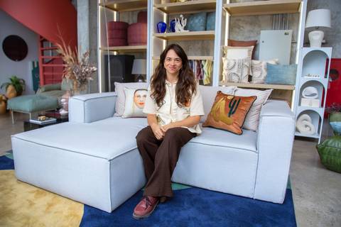 Clara Nahas sentada em sofá modular em ambiente decorado com almofadas e curadoria Westwing. Foto por Bruno Arita.'