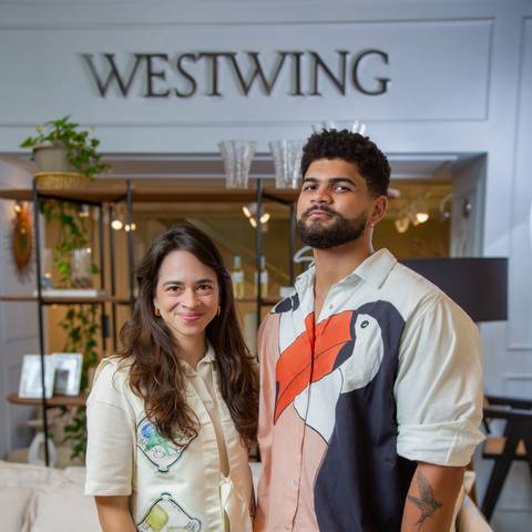 Embaixadores Clara Nahas e João Gabriel posando em frente ao logo da Westwing em São Paulo, fotografia editorial corporativa e lifestyle.'
