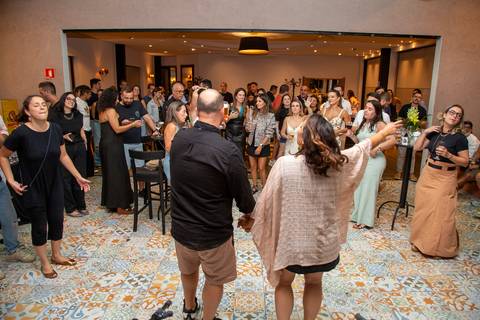 Maria e Lucas de frente para os convidados ao fundo em momento de grande comemoração no Baby Beef Jardim. Autoria de Bruno Arita.'