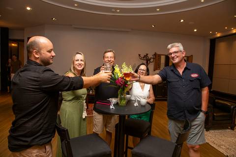 Lucas (homem careca de blusa preta) brindando com sua família em momento de celebração em Santo André. Foto por Bruno Arita.'