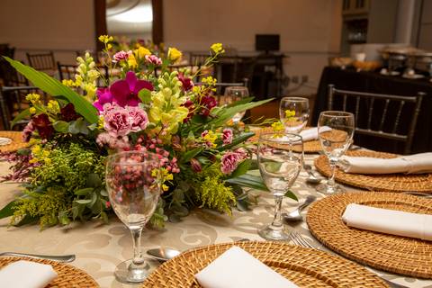 Detalhe de arranjo floral colorido em mesa posta para recepção de aniversário. Foto por Bruno Arita.'