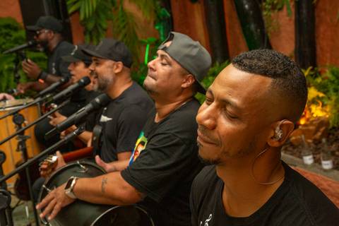 Grupo de pagode perfilado tocando em momento natural durante a feijoada de aniversário. Fotografia por Bruno Arita.'