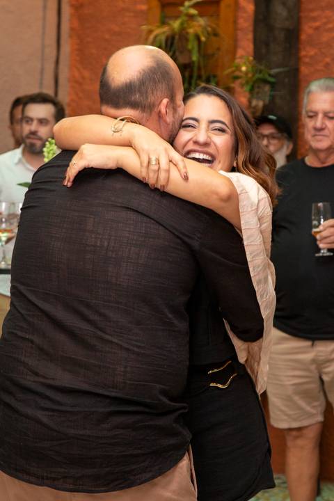 Maria abraçando Lucas amorosamente com um sorriso muito feliz no rosto. Fotografia afetiva por Bruno Arita.'