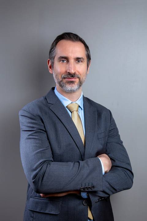 João Paulo posando de braços cruzados em ambiente corporativo, transmitindo confiança e experiência profissional. Registro por Bruno Arita.'