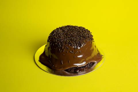 Foto de um Mini Bolo Vulcão de brigadeiro da Bem Caseirinho SP, Morumbi, com cobertura cremosa transbordando. A imagem foca na textura e no apelo visual caseiro para e-commerce e iFood.'