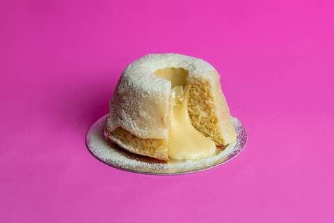 Foto de um Mini Bolo Vulcão de Ninho da Bem Caseirinho SP, Morumbi, com cobertura cremosa transbordando. A imagem foca na textura e no apelo visual caseiro para e-commerce e iFood.'