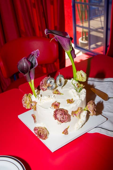 Plano fechado de bolo de aniversário de 30 anos decorado com flores naturais. Foto por Bruno Arita.'